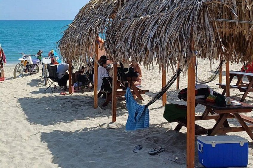 A beach with thatched umbrellas, beach chairs, and a motorcycle. 5