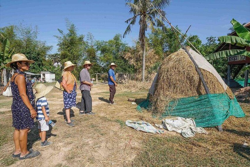 Paisaje rural con gente cerca de un hato de heno y una pequeña construcción. 5