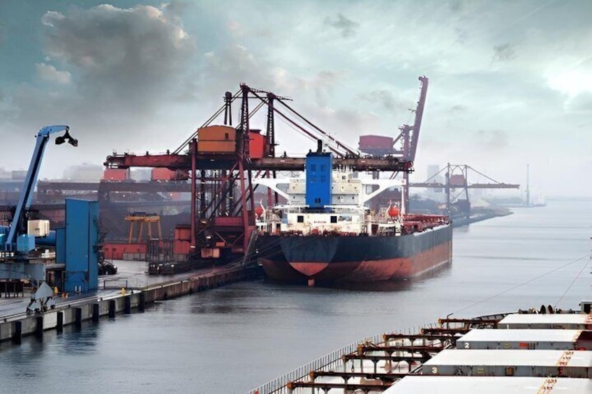 A cargo ship docked at a port with cranes and containers. 2