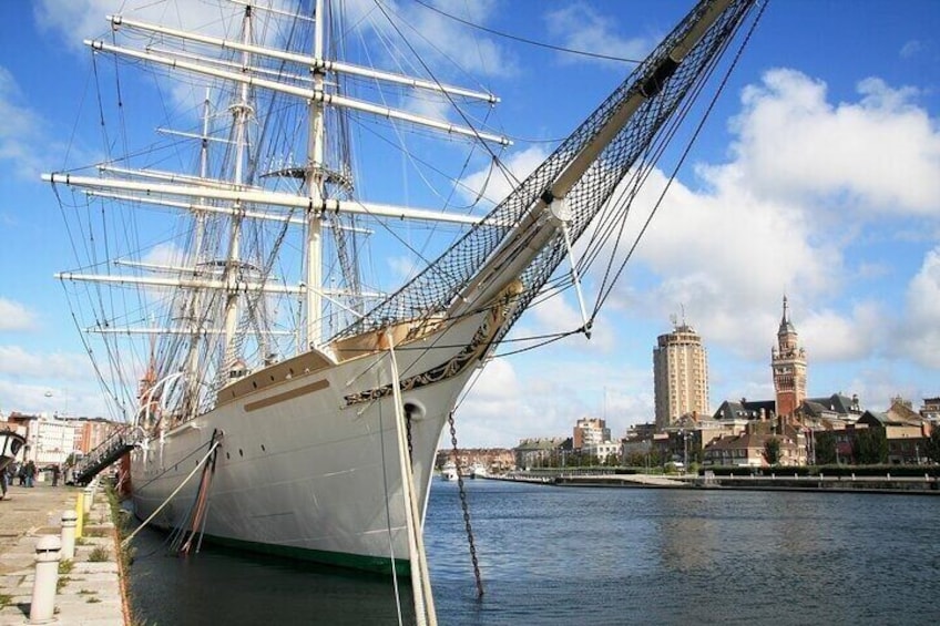 A tall ship docked by a waterfront with a city skyline in the background. 3