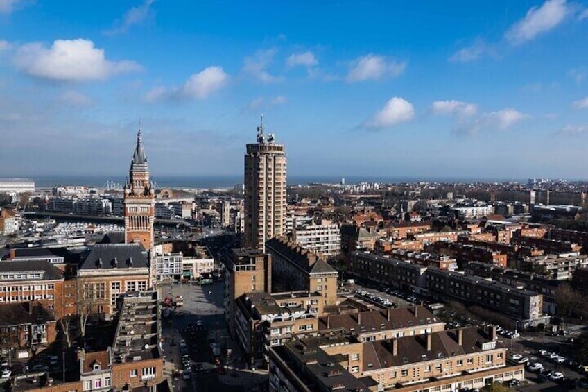 A cityscape with a prominent clock tower, a tall modern building, and dense urban architecture. 1