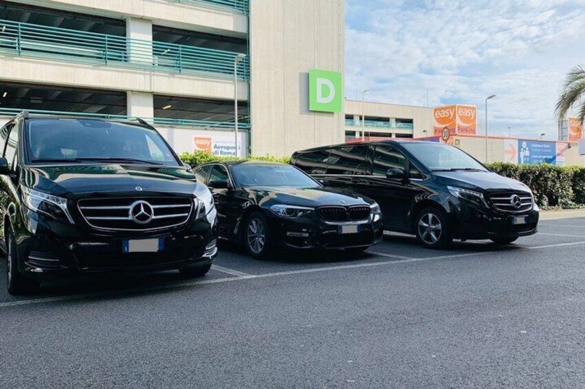Three black Mercedes-Benz cars parked in a lot with a building in the background. 5