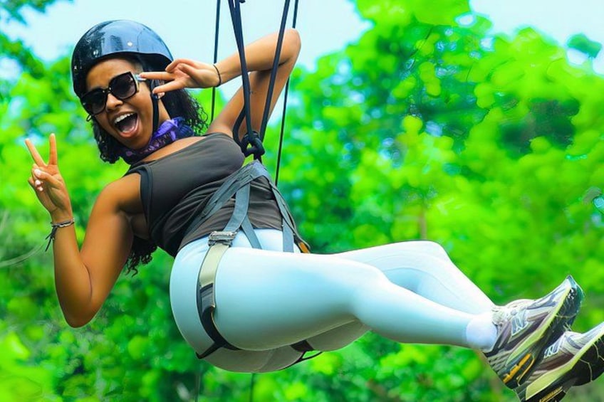 A person on a zip line with greenery in the background. 1
