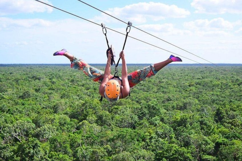 A person bungee jumping with a helmet and harness, suspended above a dense forest. 4