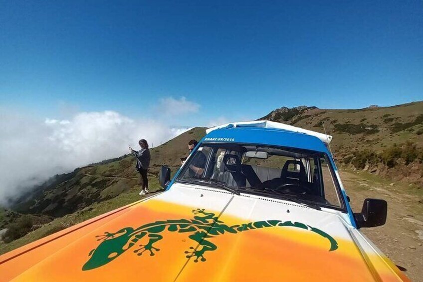 A vehicle with a blue and white roof parked on a mountain road. 5