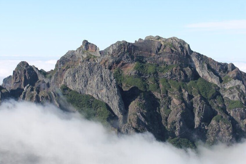 A rugged mountain range with dense vegetation and a cloud-covered base. 3