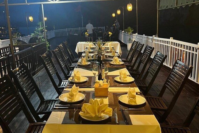 An outdoor dining area with tables set for a meal, chairs, and a railing. 3