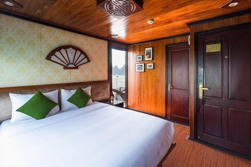 A wooden-paneled room with a large bed, a decorative fan, and a door with a sign. 5