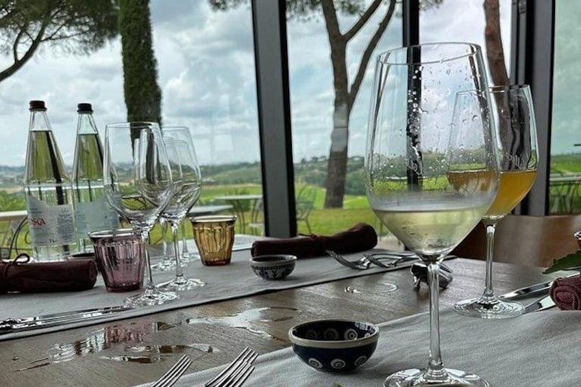 A table with wine glasses and bottles, a bowl, and a view of a landscape through a window. 5