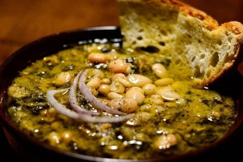 A bowl of soup with beans and onions, accompanied by a piece of bread. 4