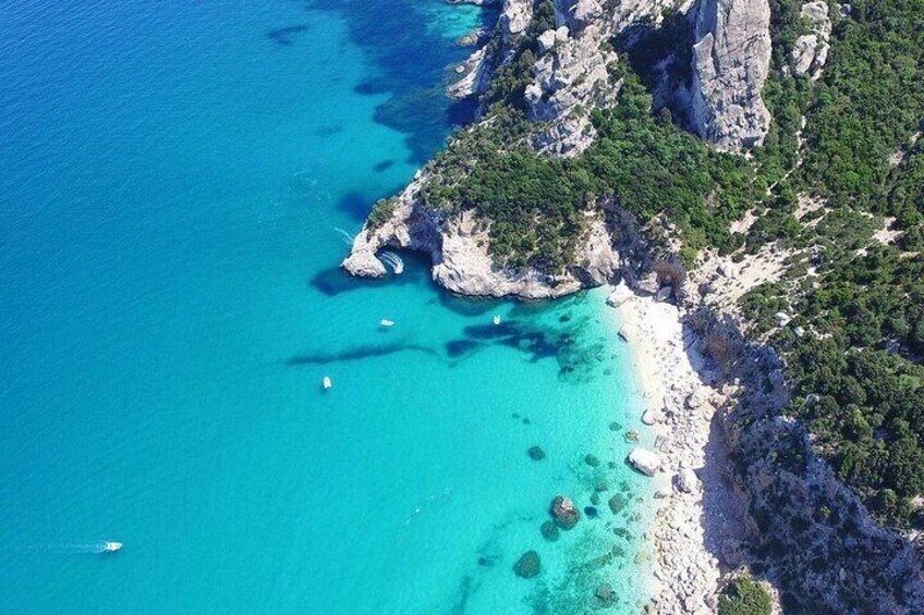 Un paysage côtier caractérisé par une eau turquoise cristalline, des falaises rocheuses et une plage de sable. 1
