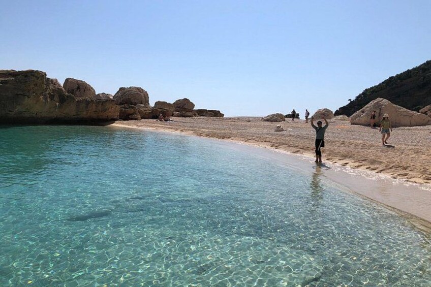 A clear beach with people walking and carrying rocks. 4