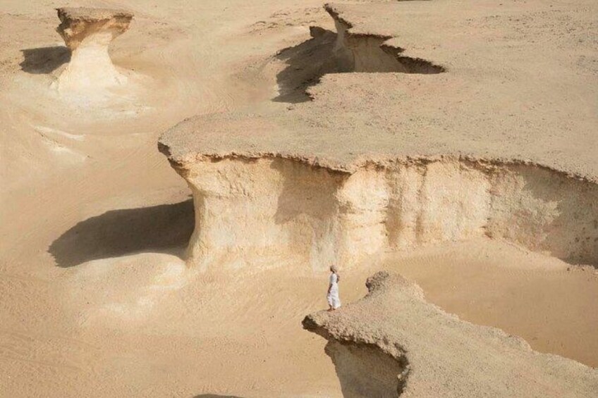 A person standing on a large rock formation in a desert landscape. 4
