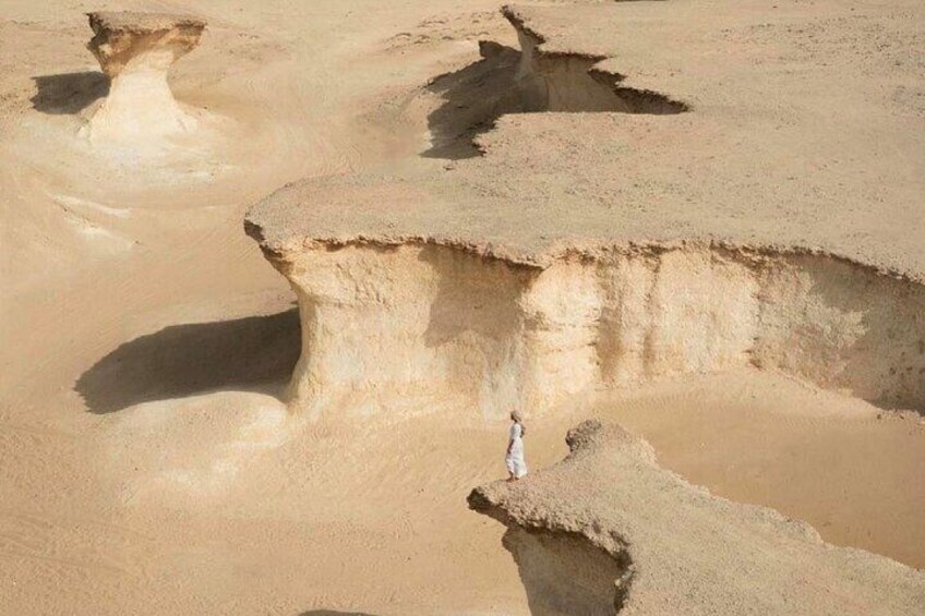 A person standing on a large rock formation in a desert landscape. 4