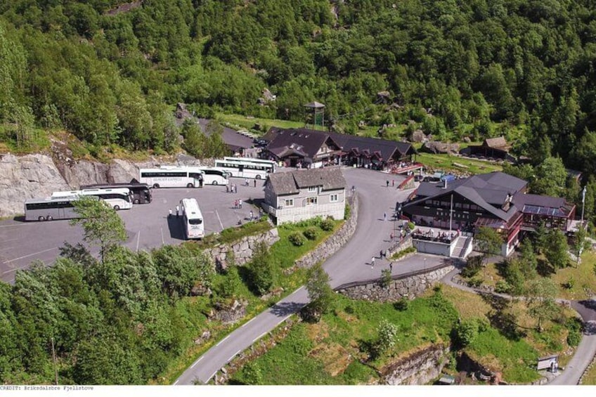 A mountainous area with a bus station, several buses, and buildings. 4