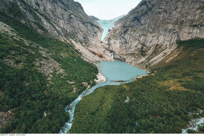 Un paysage montagneux traversé par une rivière qui serpente à travers une vallée, le tout étant bordé de forêts denses. 1