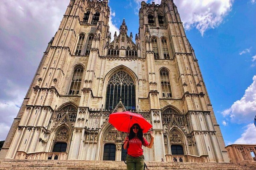 A large cathedral with intricate architecture, a person holding a red umbrella, and a clear blue sky. 4