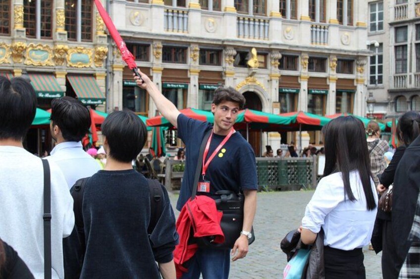 A person holding a red object, standing in front of a building with ornate architecture. 1