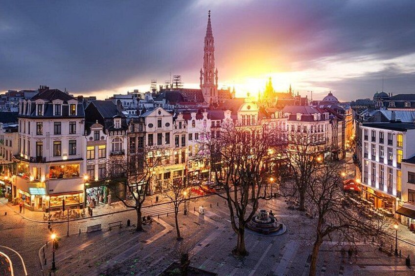 A cityscape at dusk with illuminated buildings and a prominent church spire. 2