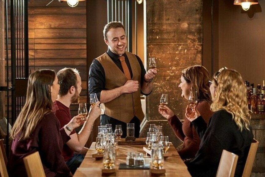 A group of people seated at a wooden table in a restaurant, with a waiter standing between them. 5