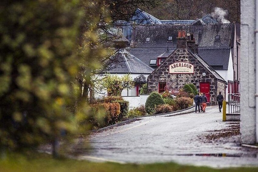 A stone building with a sign reading 'Aberlour' and a paved road leading to it. 3