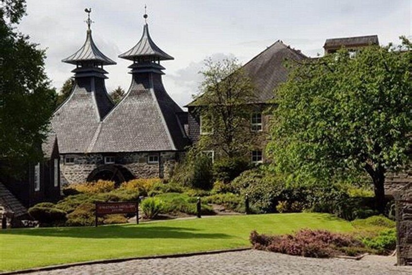 A historic building with two prominent towers, surrounded by well-maintained lawns and mature trees. 4