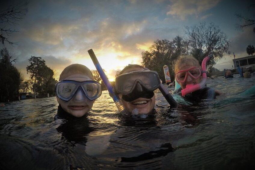 Tres personas haciendo snorkel en el agua con un atardecer de fondo. 4