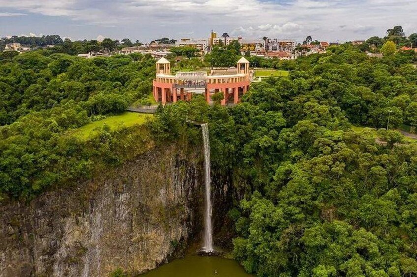 A waterfall, lush green forest, and a red building with a dome. 1
