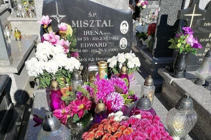 A cemetery with gravestones, flowers, and candles. 3