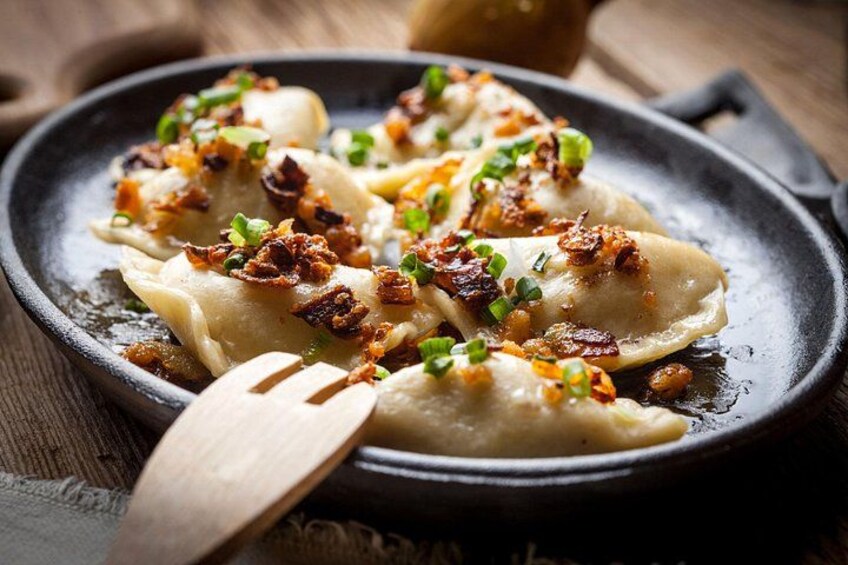 A skillet with dumplings garnished with fried onions and green onions. 2