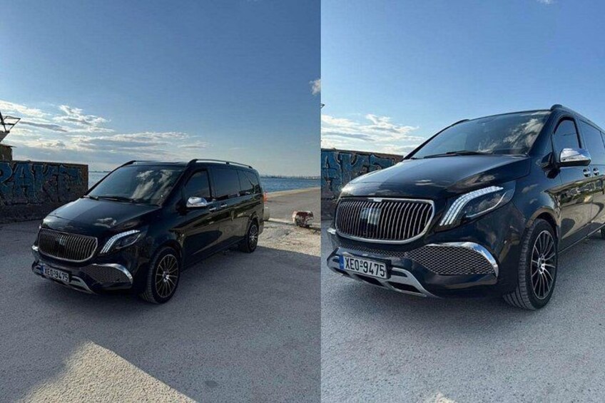 Un SUV negro estacionado en una playa, con un cielo despejado y una costa rocosa al fondo. 2