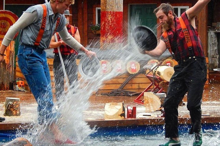 Two people splashing water at each other near a wooden structure with numbered signs. 2