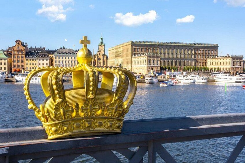 A golden crown on a bridge with a cityscape and water in the background. 3