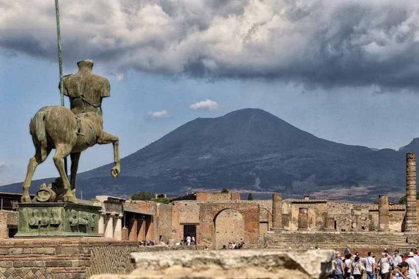 A statue of a man on horseback, ancient ruins, and a mountain in the background. 2
