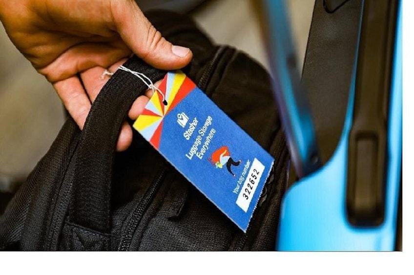 A person holding a luggage tag with a colorful design and text. 1