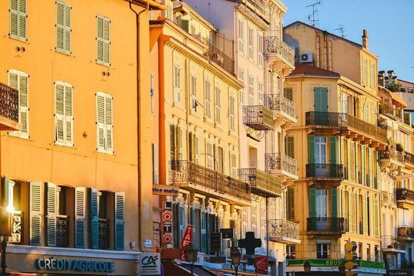 A row of colorful buildings with balconies, a sign for 'CREDIT AGRICOLE', and a 'TOILET' sign. 2