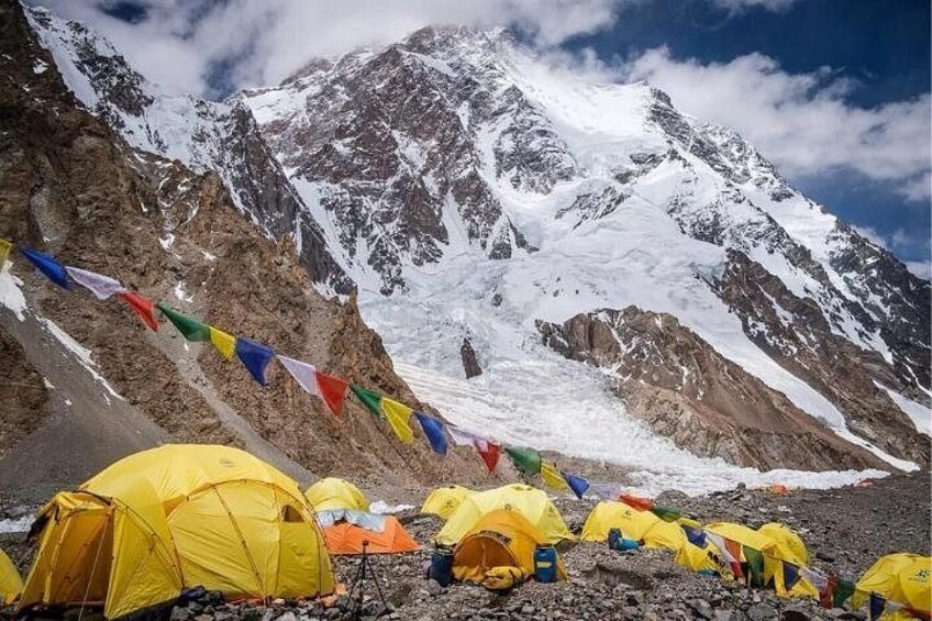Une montagne enneigée, avec des tentes et des drapeaux de prières aux couleurs vives. 2