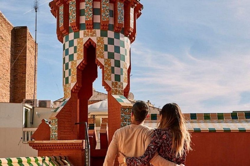 A couple standing in front of a tower with a checkered pattern, a brick building, and a clear sky. 2