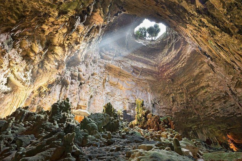 Eine Höhle mit Stalaktiten, ein Baum in einem natürlichen Bogen und eine Felsformation im unteren Bereich. 1