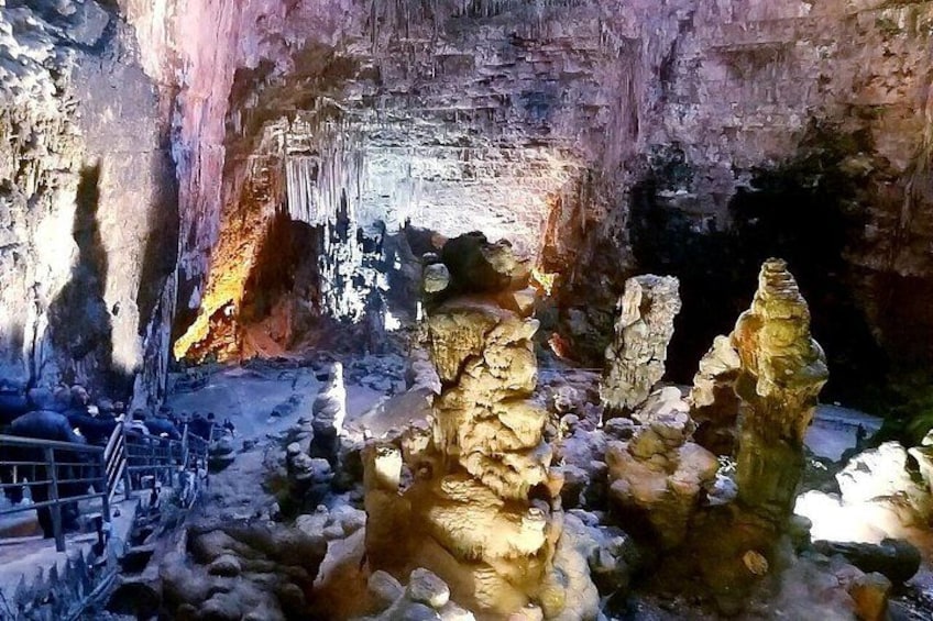 Eine Höhle mit Stalaktiten und Stalagmiten, einem Metallgeländer und einem steinigen Boden. 4