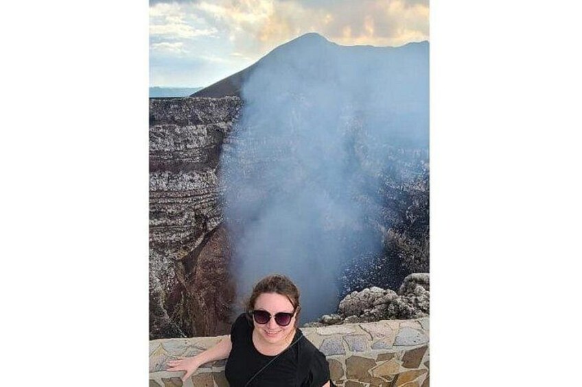 A person standing near a rocky cliff with a mountain in the background. 3