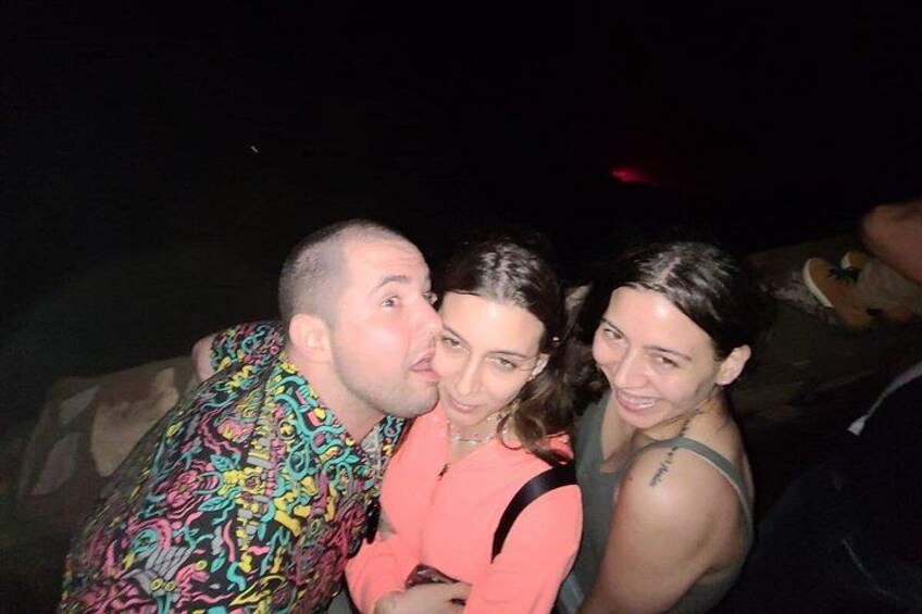 Three people in close proximity, one wearing a colorful patterned shirt, another in a pink top, and the third in a green top. 2