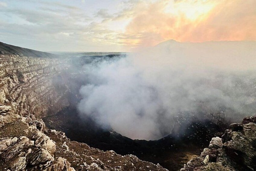 A volcanic crater with steam rising, surrounded by rocky terrain. 1