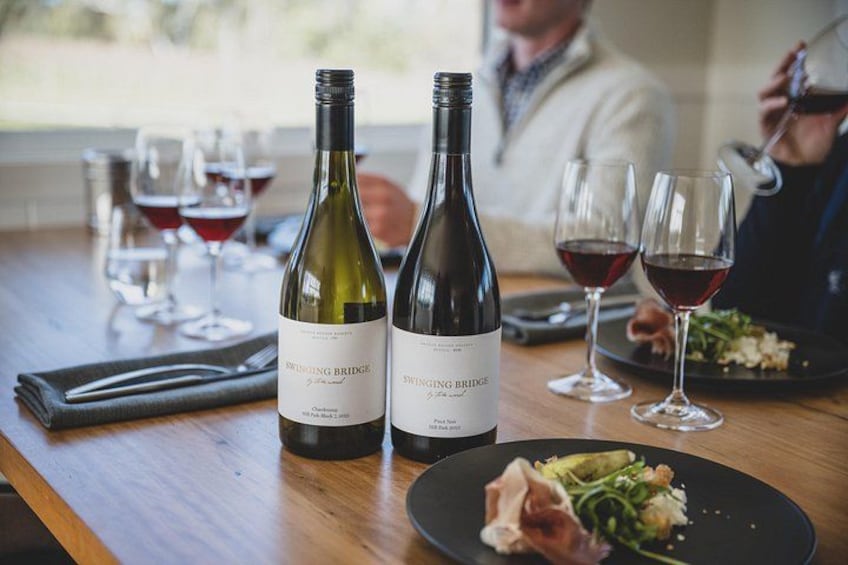 Deux bouteilles de vin, une table en bois et une assiette de nourriture. 1