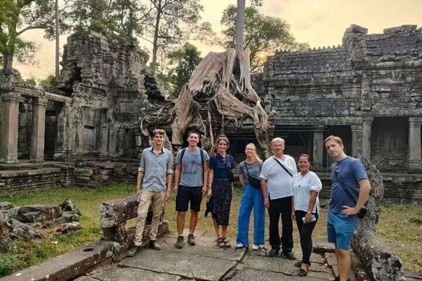 A group of people standing in front of ancient stone ruins with a large tree trunk in the center. 4