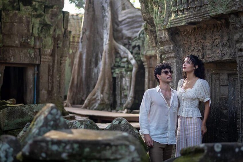 A man and a woman standing in front of ancient stone architecture with large trees. 3