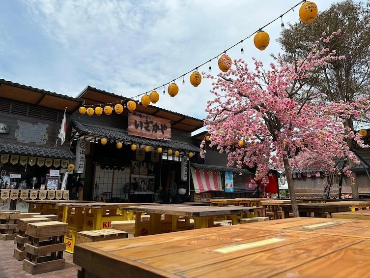 Perinteinen japanilainen ravintola, jossa on puupöydät ja -tuolit, keltaiset lyhdyt ja kirsikankukkia. 5