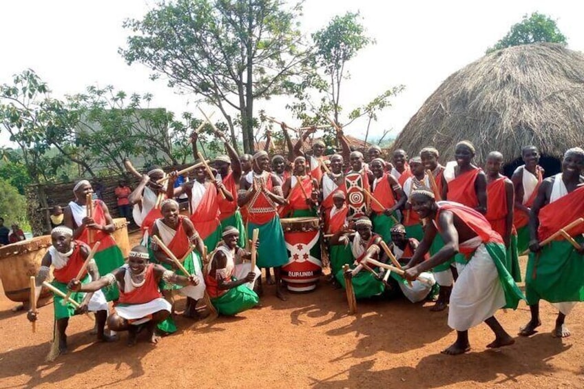 Een groep mensen in traditionele kledij die een culturele dans uitvoeren met drums en vlaggen. 1