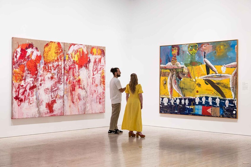 Two people in an art gallery, looking at paintings. 2