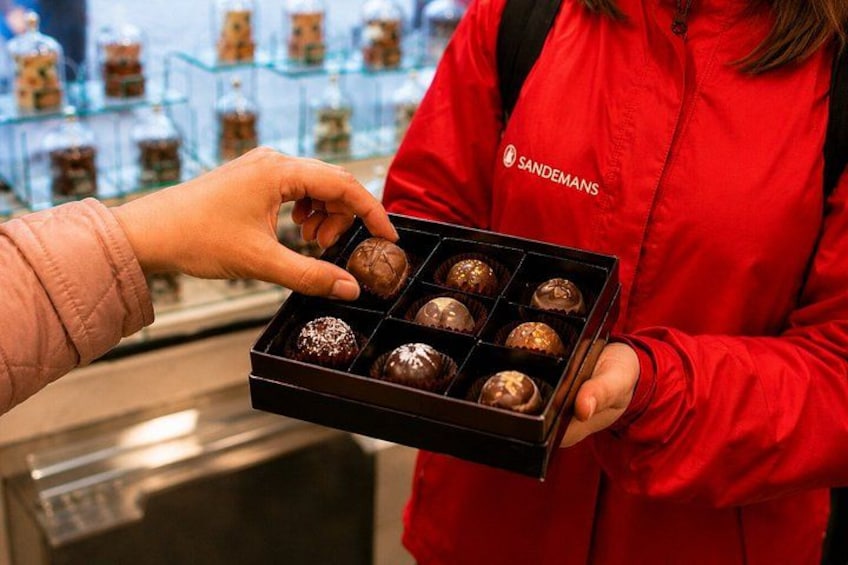A person in a red jacket holding a box of assorted chocolates. 3